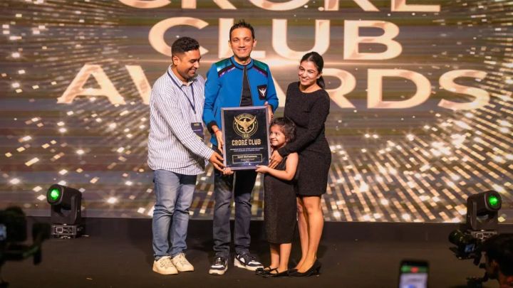Jyoti on stage with her daughter and two men, holding a Crore Club Awards plaque