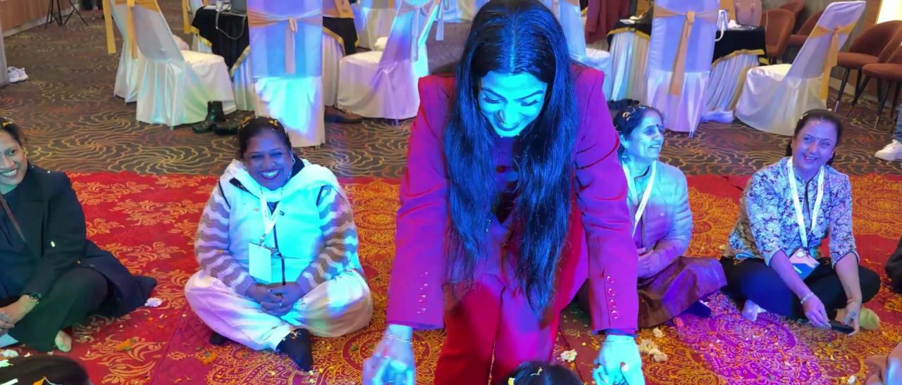 Dr. Jyoti laughing as she kneels with women in the circle