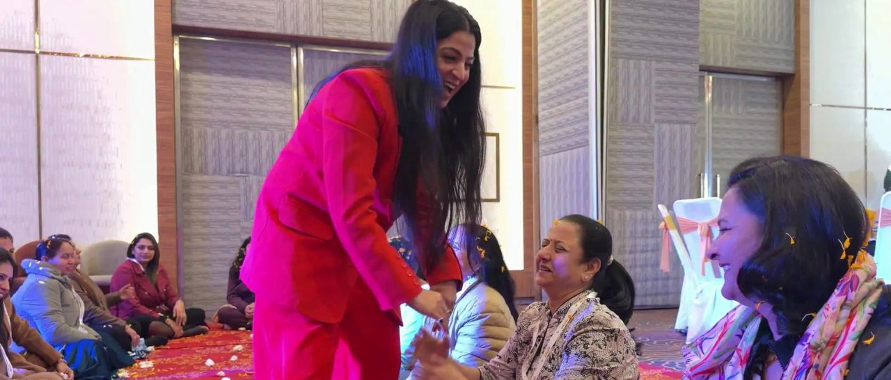 Dr. Jyoti bending down to talk with women sitting on the floor