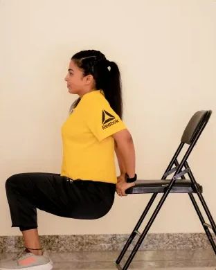 Dr. Jyoti demonstrating a chair-supported squat, a FunDa functional exercise
