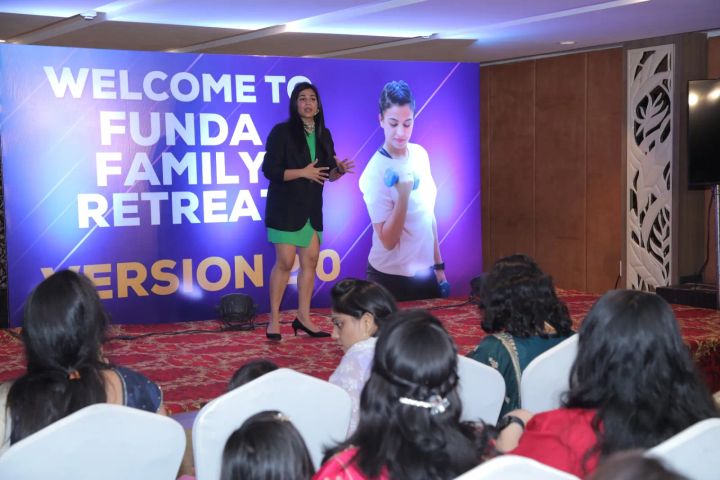 Jyoti speaking on stage to members at the FunDa Family Retreat