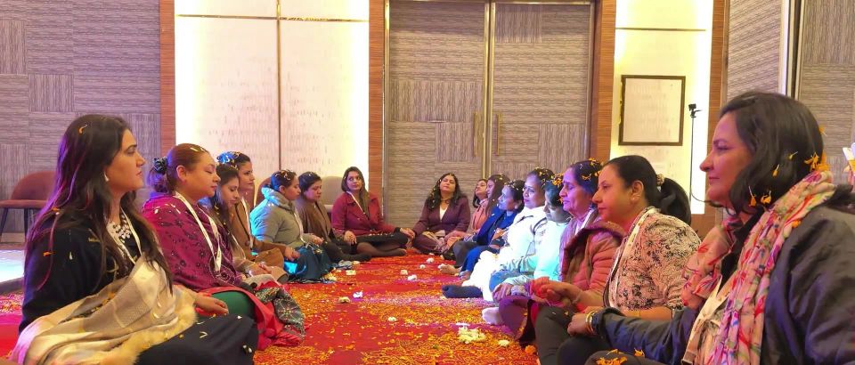 Women sitting in a large sharing circle on a red carpet
