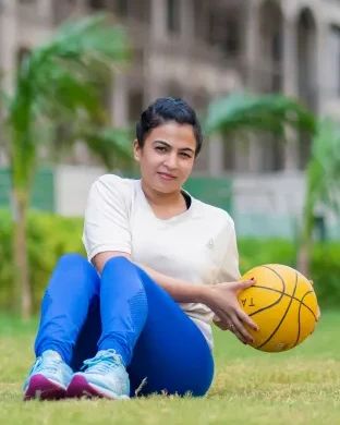 Dr. Jyoti seated on a mat, exercising with a ball